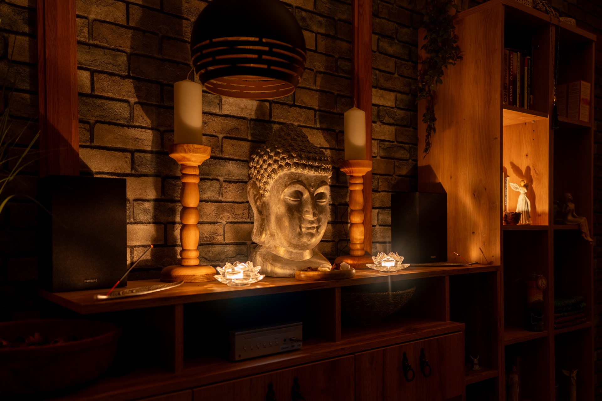 Buddha socha se svícny na cihlové stěně